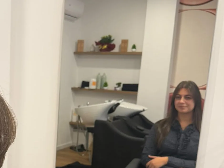 Cliente allo specchio con la zona lavaggio di Maison Hair sullo sfondo di Maison Hair a Conversano